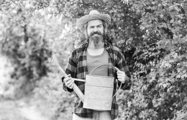 Besin içeren doymuş toprak. Adam bahçesinde sulama tenekesi olan büyük bir adamı tutuyor. Bahçe işleri ve sulama bitkileri. Bahçe işleri konsepti. Yaz sıcağı. Ekipmanlar çiftçilerin elinde. Kırsal biçim