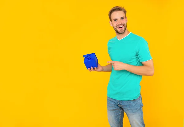 Mutlu traşsız genç adam işaret parmağı sarı arka plandaki mevcut kutuda, boks günü — Stok fotoğraf