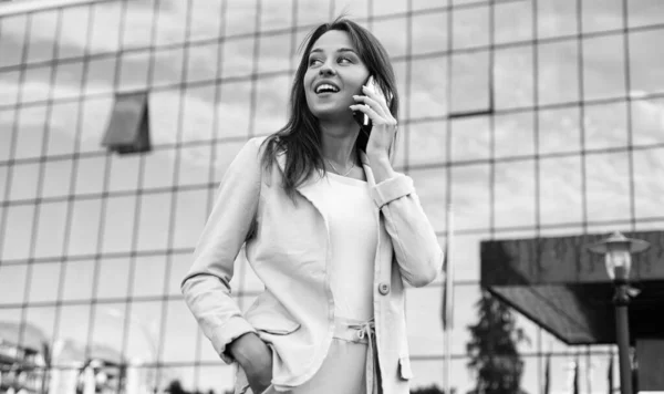 Una hermosa joven feliz dama de negocios de pie en la calle de la ciudad y hablando por teléfono móvil, conversación — Foto de Stock