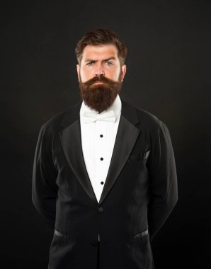 Siyah arka planda smokin giyen sakallı damat, resmi kıyafetler.