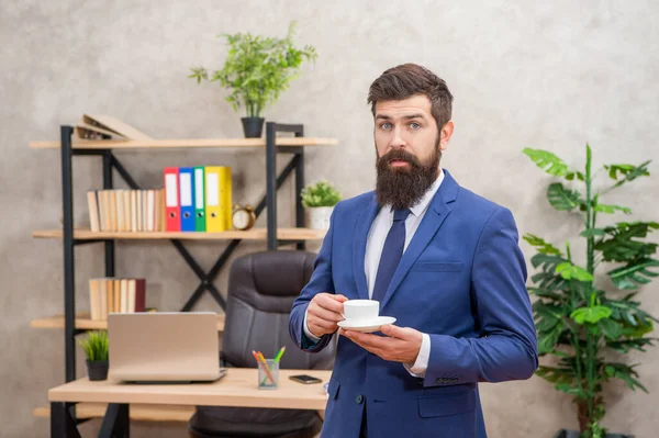 Asombrado ceo brutal en traje de negocios celebrar taza de café de la mañana en la oficina, pausa para el café — Foto de Stock