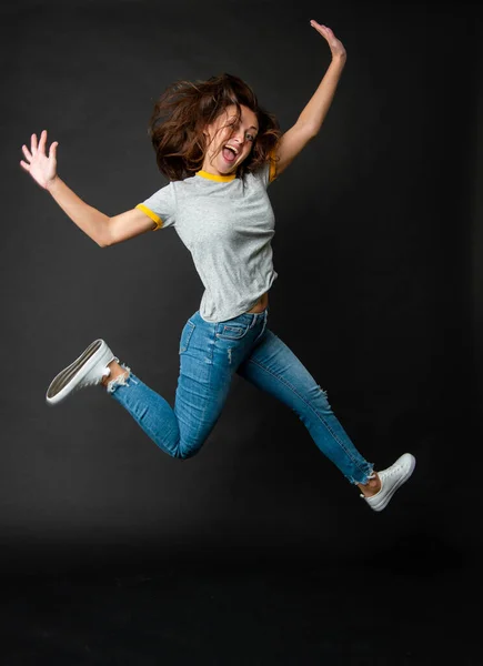 Feliz legal extático enérgico menina pulando até midair escuro fundo, salto — Fotografia de Stock