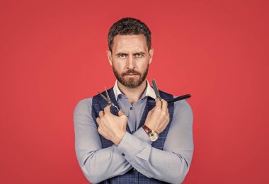 Sakallı adam, kırmızı arka planı kesmek ve traş etmek için eski berber aletlerini tut, berber.