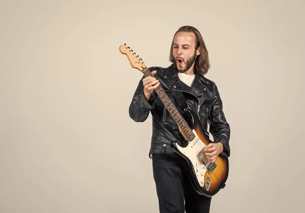 Érzelmi szakállas rockzenész elektromos gitározik bőrdzsekiben, zenében — Stock Fotó