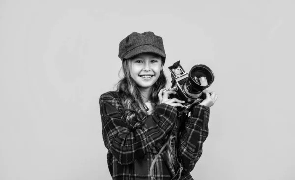 Párizsi retró kinézet. francia alkalmi divat. Boldog lány fotós kockás kabátban. A tavaszi gyerek fényképezőgépet használ. A gyerek divatos kalapot visel. vintage technológia. gyermekkori boldogság — Stock Fotó