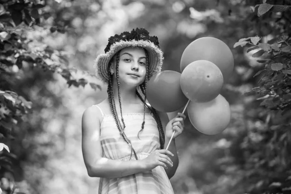 Счастливая девочка в соломенной шляпе с цветами роз летом природа с воздушными шарами для вечеринок, радость — стоковое фото