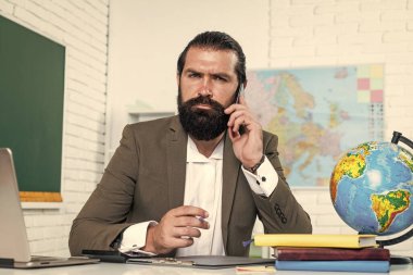 Ciddi, olgun bir öğretmen telefonda konuşuyor. Vahşi sakallı adam sınıfta çalışıyor ve Hols akıllı telefonu kullanıyor. Çevrimiçi sınava hazırlanın. Ders üzerine ders veren üniversite hocası. Okula dönüyorum. resmi eğitim. iletişim