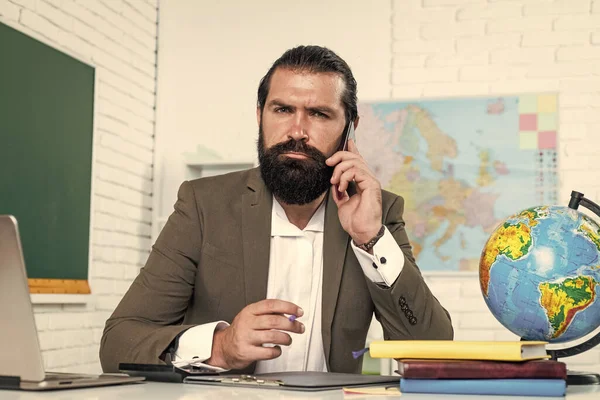 Ciddi, olgun bir öğretmen telefonda konuşuyor. Vahşi sakallı adam sınıfta çalışıyor ve Hols akıllı telefonu kullanıyor. Çevrimiçi sınava hazırlanın. Ders üzerine ders veren üniversite hocası. Okula dönüyorum. resmi eğitim. iletişim