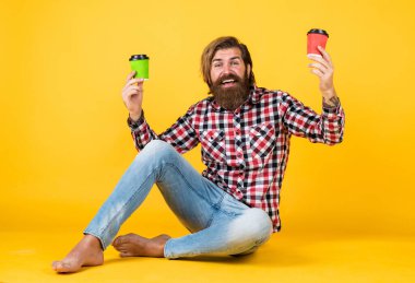 Gelmiş geçmiş en iyi içki. Beyaz bardak tutan yakışıklı sakallı adam. Bardakla içecek. Çay ya da kahve içmek. Günaydın. Evde sabah havası var. İlham konsepti. hippi adam kahve içer.