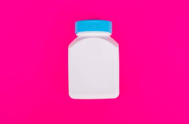 multivitamin kavanozu pembe arka planda beyaz renk, vitamin