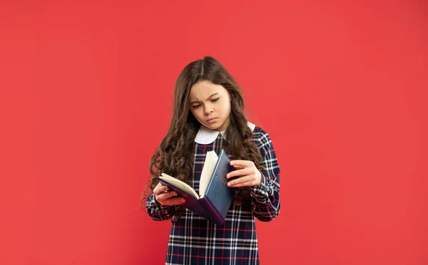 Miúdo curioso segurar notebook em fundo vermelho, estudo — Fotografia de Stock