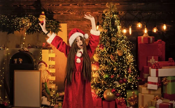 最後に。幸せと喜び。子供の幸せな興奮した女の子とクリスマスツリーの近くの贈り物。メリークリスマス。幸せな子供時代のコンセプト。キッド・サンタ・ハット。奇跡の時だ。愛を広げるんだ。12月のアクティビティ — ストック写真