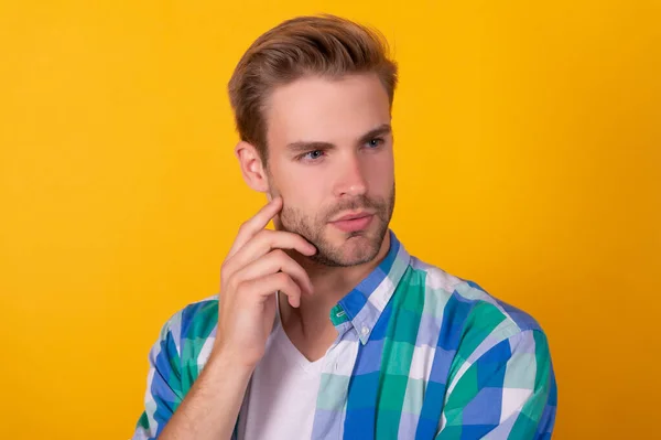 Portrait of serious young man with thoughtful face thinking yellow background, think — Stockfoto