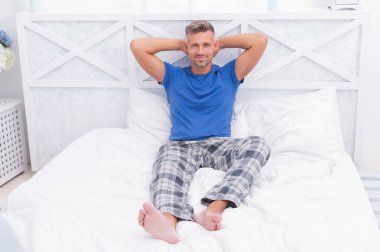 Uyan ve gülümse. Pijamalı mutlu adam yatakta rahatlıyor. Sabah uyanmak. Sabah titreşimleri