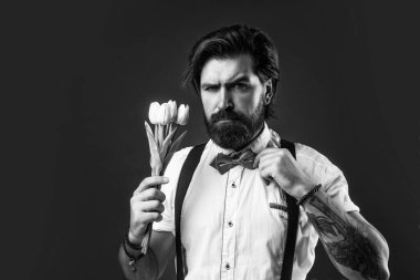 Hayatın gelişmesine izin ver. Askılı ve papyonlu romantik bir adam. Kendine güvenen ve zarif bir adam lale çiçekleri tutar. Aşk randevusu için hediye. Buketli eski moda sakallı hippi. Bahar çiçeği hediyesi