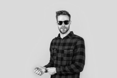 Kareli tişörtlü ve güneş gözlüklü genç yakışıklı adamın yüzünde kıllar, moda aksesuarları var.