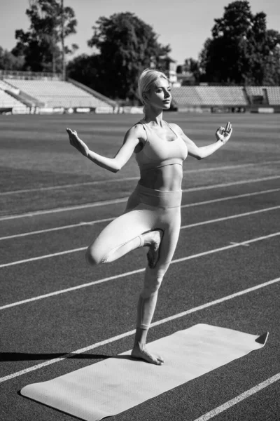 Mulher atlética em fitness desgaste praticando ioga no estádio, ioga — Fotografia de Stock