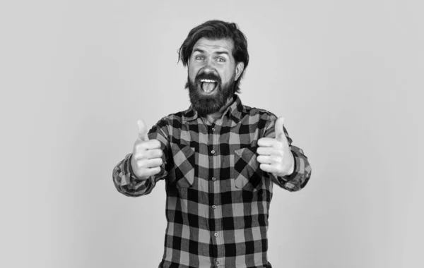 Homme heureux en chemise à carreaux. homme émotionnel sur fond jaune. brutal hipster barbu. mec mature avec une moustache sur le visage. exprimant des émotions humaines. les pouces levés — Photo