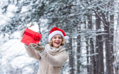 Yeni yılınız kutlu olsun. Noel tatili. Hediye zamanı. Kırmızı Noel Baba şapkalı kadın hediye kutusunu tutuyor. Boks günü. Kış alışverişi. hediye ve sürpriz konsepti. Herkese mutlu noeller.
