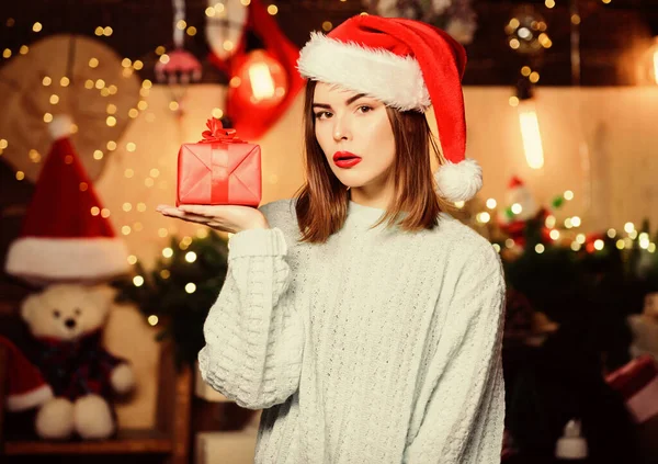 Chica elegante maquillaje labios rojos celebrar regalo de Navidad. Ambiente acogedor de Navidad. Cree en el milagro. Sombrero de Santa Claus mujer en Nochebuena. Señora cara adorable celebrar la Navidad en casa. Abre su regalo. —  Fotos de Stock