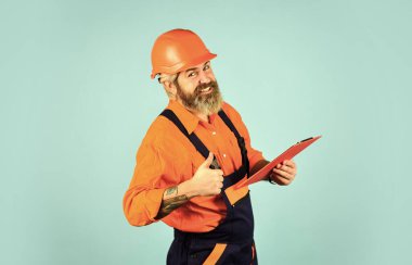 Belgelerle ustabaşı. Teftiş. Kontrol konsepti. İnşaat malzemeleri teslimatı. Elinde dosya tutan kasklı bir adam bilgi arıyor. Tadilat için malzeme al. Sakallı bir dükkancı. Kontrol Listesi