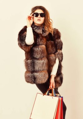 İndirim ve satış. Kara Cuma 'da indirimle alın. Alışveriş mi yoksa doğum günü hediyesi mi? Kadın alışveriş butiği. Güneş gözlüğü ve kürklü ceket giyen bir kız beyaz arka plan alışverişi yapıyor. Bayan alışveriş torbaları.