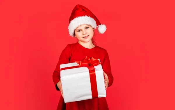 Xmas hediye alışverişi. Hediye paketi. Promosyon amaçlı. Başkasına ver. Mutlu Noeller ve mutlu Noeller. Kış tatili Küçük kız Noel Baba şapkası hediye kutusu. Çocuk şimdiki kutucuğu kırmızı arkaplanda tut — Stok fotoğraf