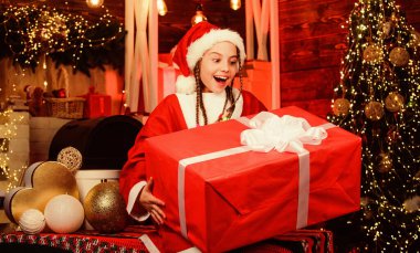 Çocuk Noel arifesinde eğleniyor. Mutluluk ve neşe. Kız Noel Baba kostümü hediye edildi. Noel Baba ekibi. Noel Baba partisi. Mutlu yıllar. Büyük sürpriz. Kış hediyesi. Cömert bir tatil. Tatmin edici konsept