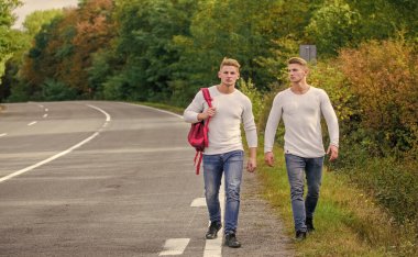 Arabanın kolayca kenara çekebileceği bir yer seç. Erkekler sırt çantasıyla yürüme yolu. İkizler yol boyunca yürür. Macera konsepti. Yolda otostop çeken adamlar. Turist gezgini otomobil durağında durur. Sorunlar taşınıyor