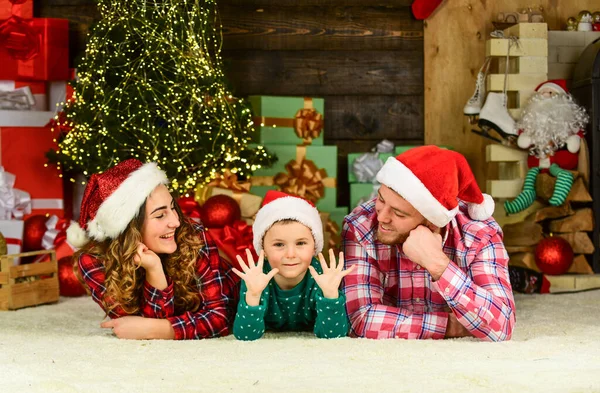 Karácsonykor együtt. a szülők a fiukkal télapó kalapot viselnek. apa és anya a gyerekkel otthon maradnak nyaralni. Boldog karácsonyt! Anya, apa és a kisgyerek jól érzik magukat a bulin. boldog család ünnepli az új évet — Stock Fotó