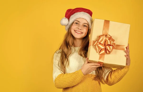 새해 복 많이 받아. 온라인으로 크리스마스 쇼핑하기. 할인받을 시간입니다. 웃는 아이가 물건을 들고 있습니다. 선물도 주고 산타 클로스의 선물도 주고. 노란 배경의 작은 소녀 산타. xmas 파티. 복사 공간 — 스톡 사진