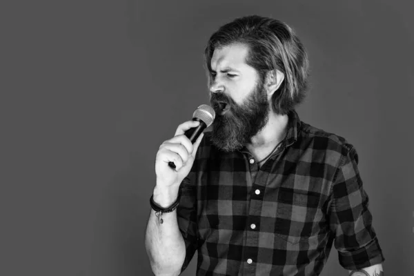 La musique est le langage universel de l'humanité. homme barbu en chemise à carreaux chanter chanson. mec occasionnel exprimer des émotions humaines tout en chantant. hipster émotionnel avec micro. chanteur masculin avec microphone. karaoké — Photo