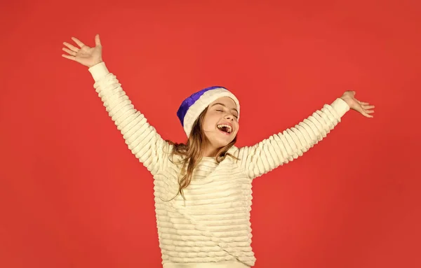 Kerstvakantie uitnodiging. Dagen tellen tot Kerstmis. Kerstfeest. Ik kan emoties niet tegenhouden. Schattig meisje draagt kerstman hoed rode achtergrond. Emotionele gezichtsuitdrukking. Gelukkige jeugd — Stockfoto