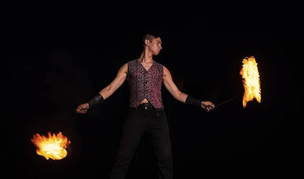 Fire performer man perform burning poi spinning in darkness outdoors, performing