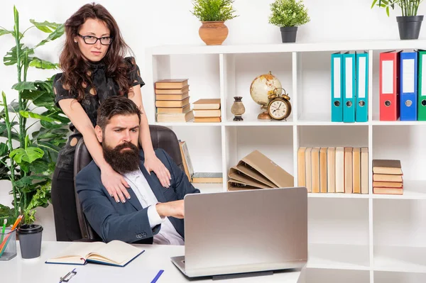 职业女性拥抱在办公室笔记本电脑上工作的男人，职场恋情 — 图库照片