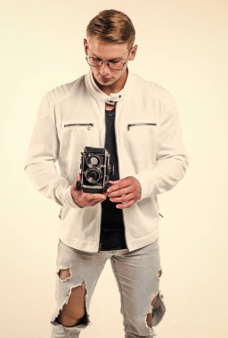 Gözlüklü yakışıklı genç adam. Retro fotoğraf makinesini tut. Beyaza izole edilmiş, çekim yapıyor.