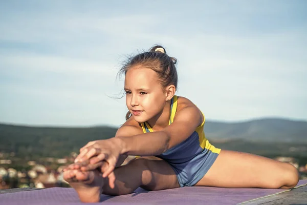 Grote vooruitgang. gezondheid en fitness. gymnastiek. gelukkig tiener meisje op lucht achtergrond. Het kind heeft een flexibel lichaam. kind in sport kleding training. concept van uitrekken en opwarmen. kindergeluk — Stockfoto