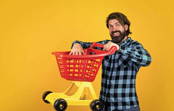 Glücklicher Mann mit Einkaufswagen über gelbem Hintergrund, Shopper im Geschäft — Stockfoto