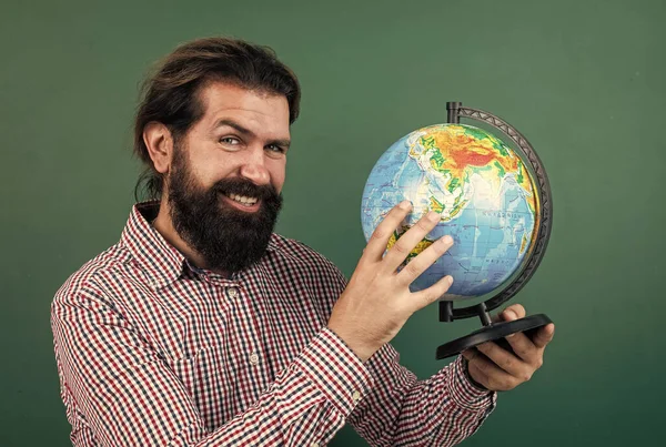 いい笑顔だ。勉強の準備ができてる。非正規教育です。地理の授業中に学校の教室で男子生徒。試験に合格だ。主題を学ぶことです。ひげを生やした幸せな地理学者は地球を見て — ストック写真
