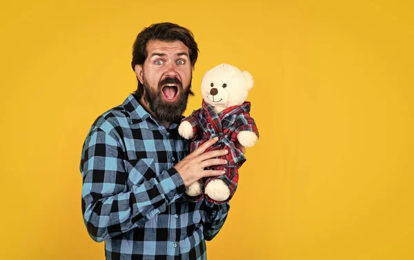 真是个惊喜快乐的男人抱着泰迪熊。穿着格子衬衫和熊玩具的快乐男人。快乐和喜悦的感觉。祝您节日快乐。玩具店的大胡子嬉皮士。做我的情人。复制空间 — 图库照片