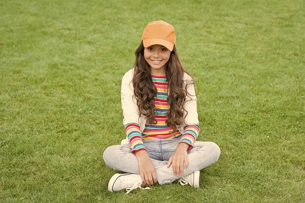 Glückliches Schulalter weibliches Kinderlächeln sitzt auf grünem Gras, Mädchen — Stockfoto