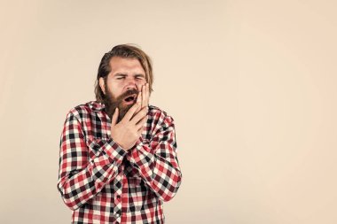 dişçi muayenesi. Sıradan kıyafetler içindeki yakışıklı sakallı adam. Acı çeken beyaz bir adam. Vahşi sakallı hippinin dişleri ağrıyor. Erkek dişlerinde ağrı hisseder. Sıradan bir erkeğin tıbbi bakıma ihtiyacı var.