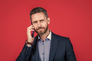Takım elbiseli olgun bir adam cep telefonuyla konuşuyor, iş görüşmesi.