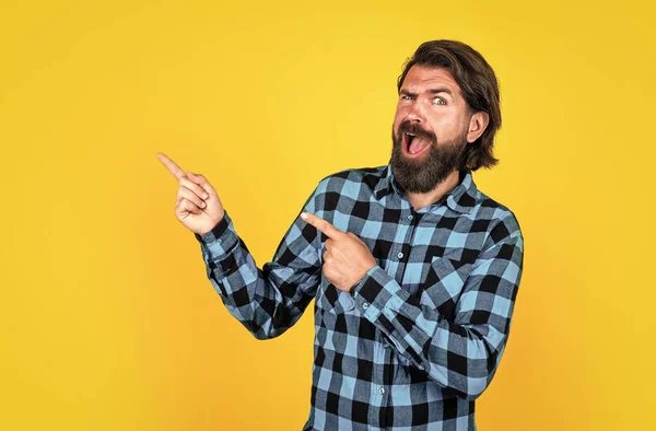 Retrato de um homem surpreso com bigode apontando o dedo para longe em um fundo amarelo, anúncio — Fotografia de Stock