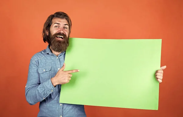 Look over there. brutal caucasian hipster hold paper shit, copy space. human emotions. unshaven guy with groomed long hair. barbershop and hairdresser. male beauty and fashion. happy bearded man — 스톡 사진