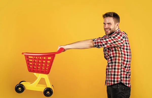 Stylish male carry shopping cart. bearded man in shop store. buy and purchase. prepare for holidays. householding. real shopaholic. young guy in checkered shirt go shopping — Stock Photo, Image