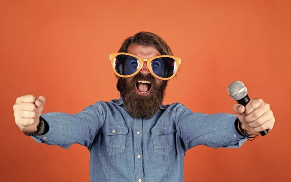 Guten Tag. Männer singen Musik in Mikrofon. Lustiger bärtiger Mann mit Mikrofon. Brutaler kaukasischer Hipster mit Partybrille. Karaoke-Sängerin. unrasierter Typ mit gepflegten langen Haaren — Stockfoto