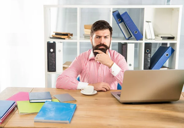 Vakava mies työpaikalla. Ajatteleva mies istuu toimistopöydällä — kuvapankkivalokuva