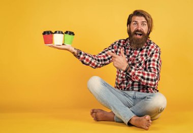 Mutlu, sakallı, sakalsız, şık saçlı, sıradan kıyafetler giyen, kahve içen, kahve mahsulü sunan yakışıklı adam.