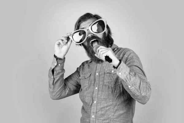 Mature bearded guy has long hair wearing party glasses and singing in mic, fun — Foto Stock